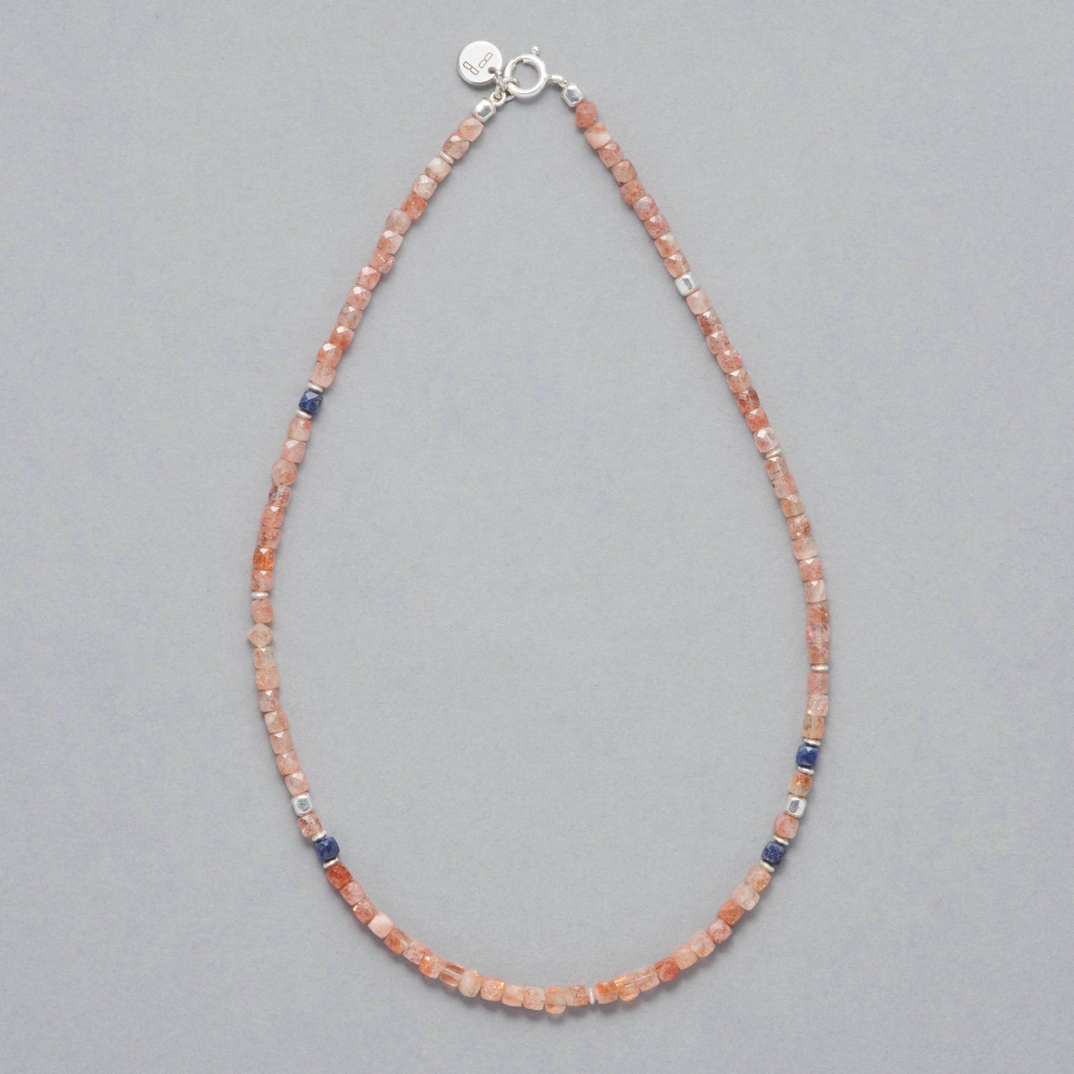 Product shot of the Ginger Necklace made with faceted square Sunstones, faceted square Sapphires and Sterling Silver elements. 