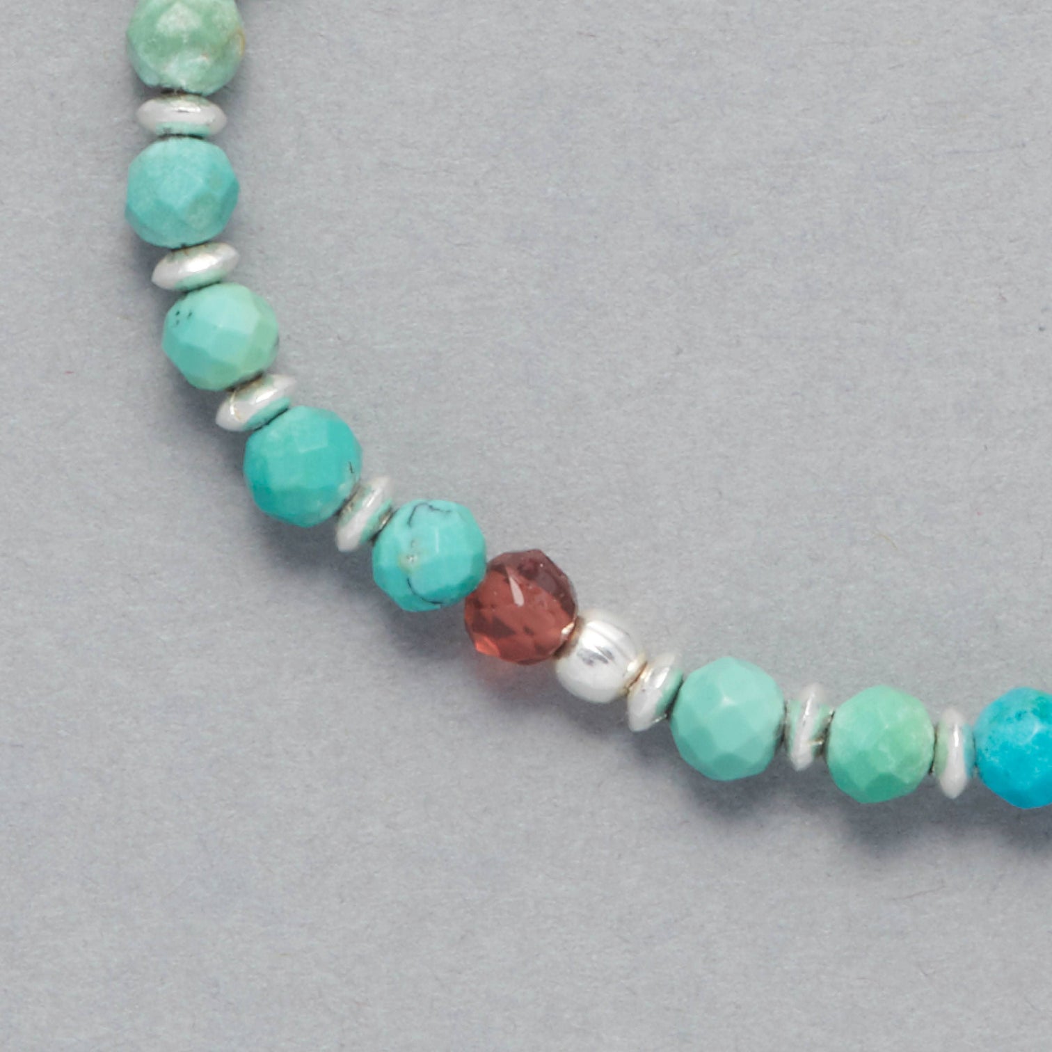Detail shot of the Kya Bracelet made with faceted Turquoise, faceted Garnet and Sterling Silver Elements. 