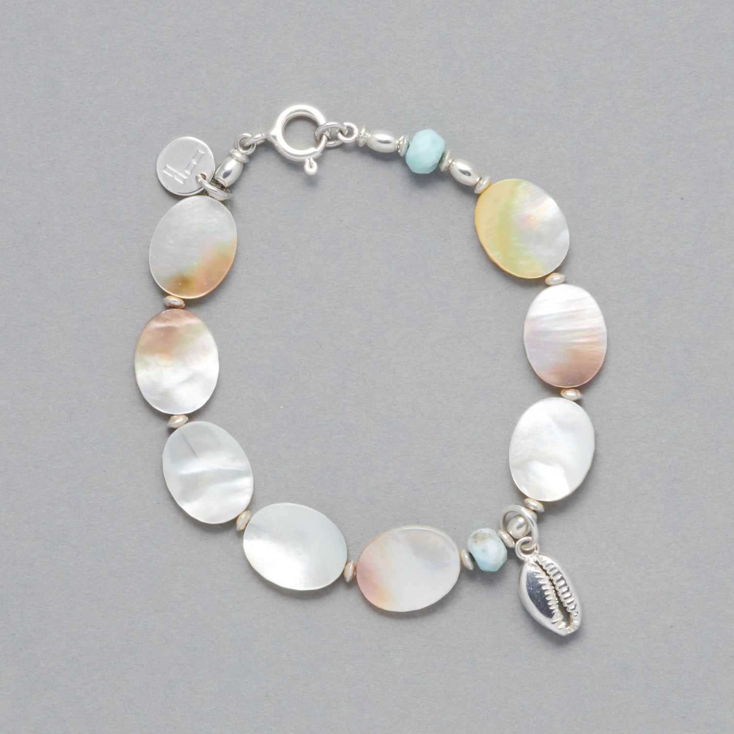 Product shot of the MARILLA Bracelet made with Larimar, Mother of Pearl, Sterling Sliver elements and a Seashell Charm.