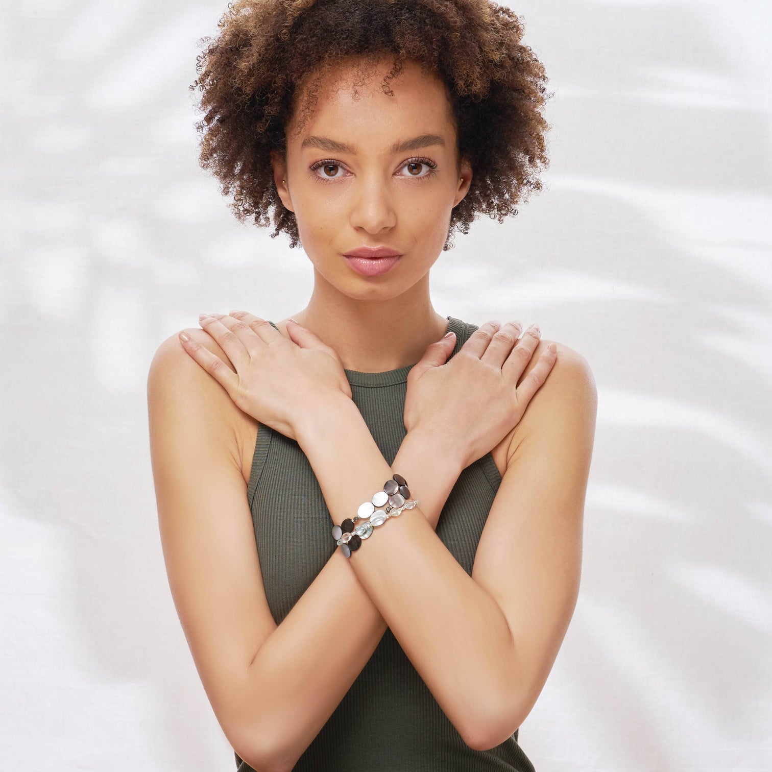 A female model is wearing the Stella bracelet made with Mother of Pearl and the Zoe bracelet made with Aquamarine.