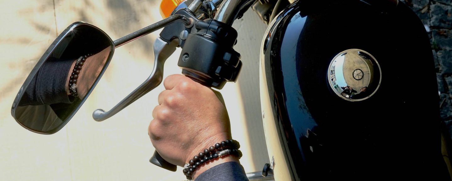 Close-up of a man on a motor bike. He is wearing two bracelets. Maxim made with Ebony and Kane made with Mahogany Obsidian.