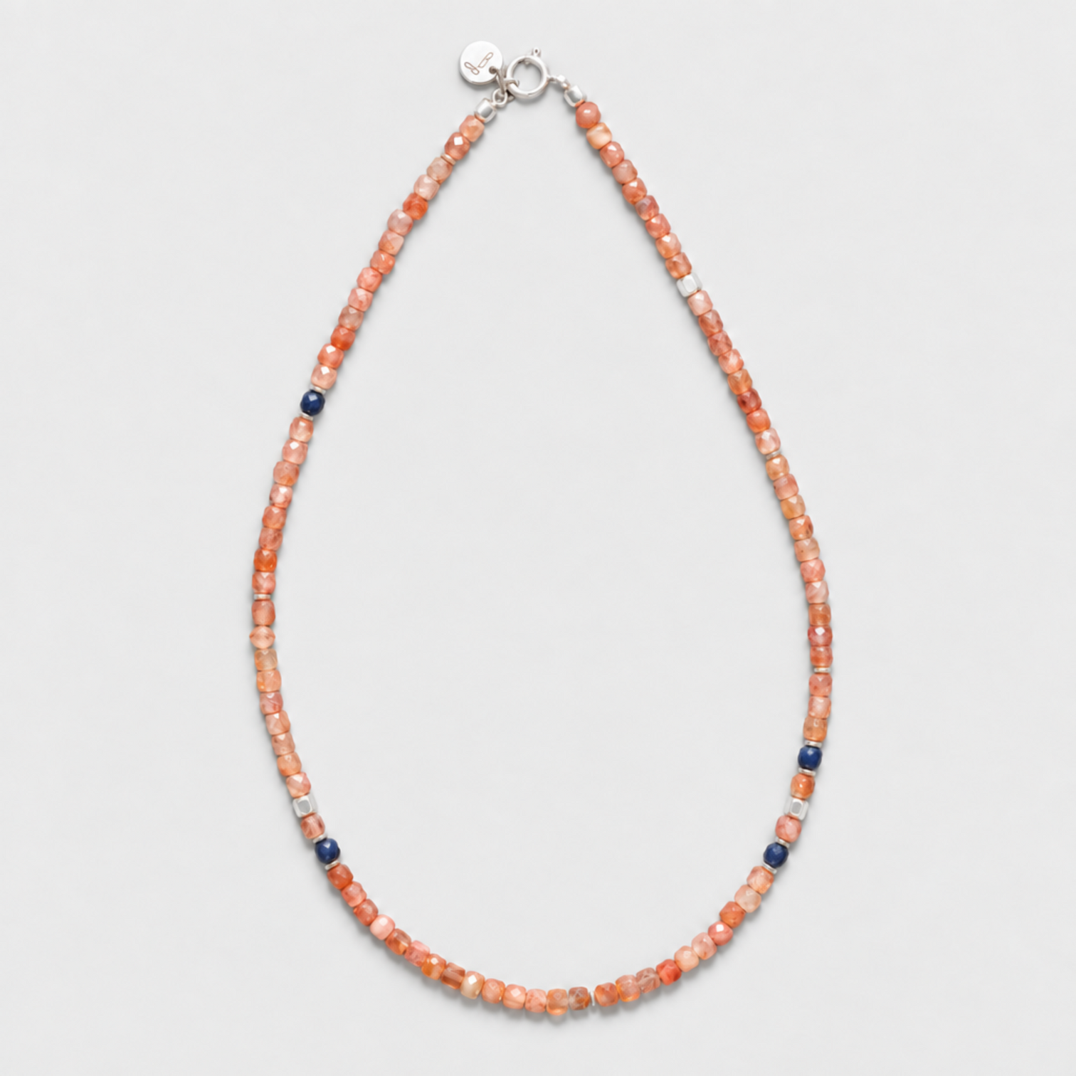 GINGER necklace with peach sunstones, blue sapphires and sterling silver clasp on a neutral light-grey background.