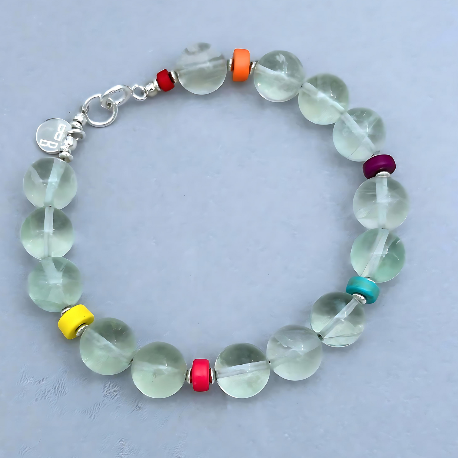 The JENIFER Bracelet is a fun and uplifting accessory. The beautiful pale blue Fluorite Beads combined with rainbow-hued Howlite Discs are everything else but boring. 