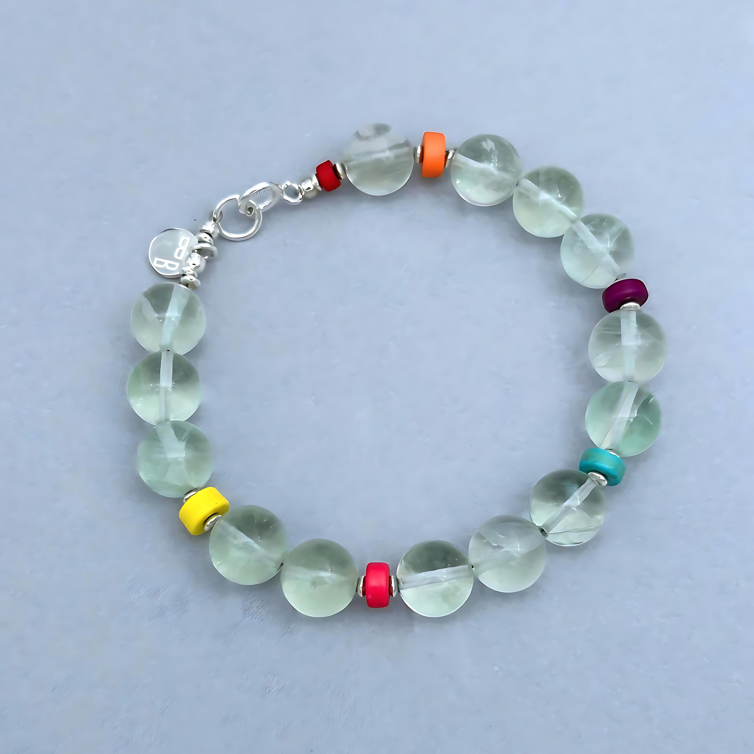 The JENIFER Bracelet is a fun and uplifting accessory. The beautiful pale blue Fluorite Beads combined with rainbow-hued Howlite Discs are everything else but boring. 