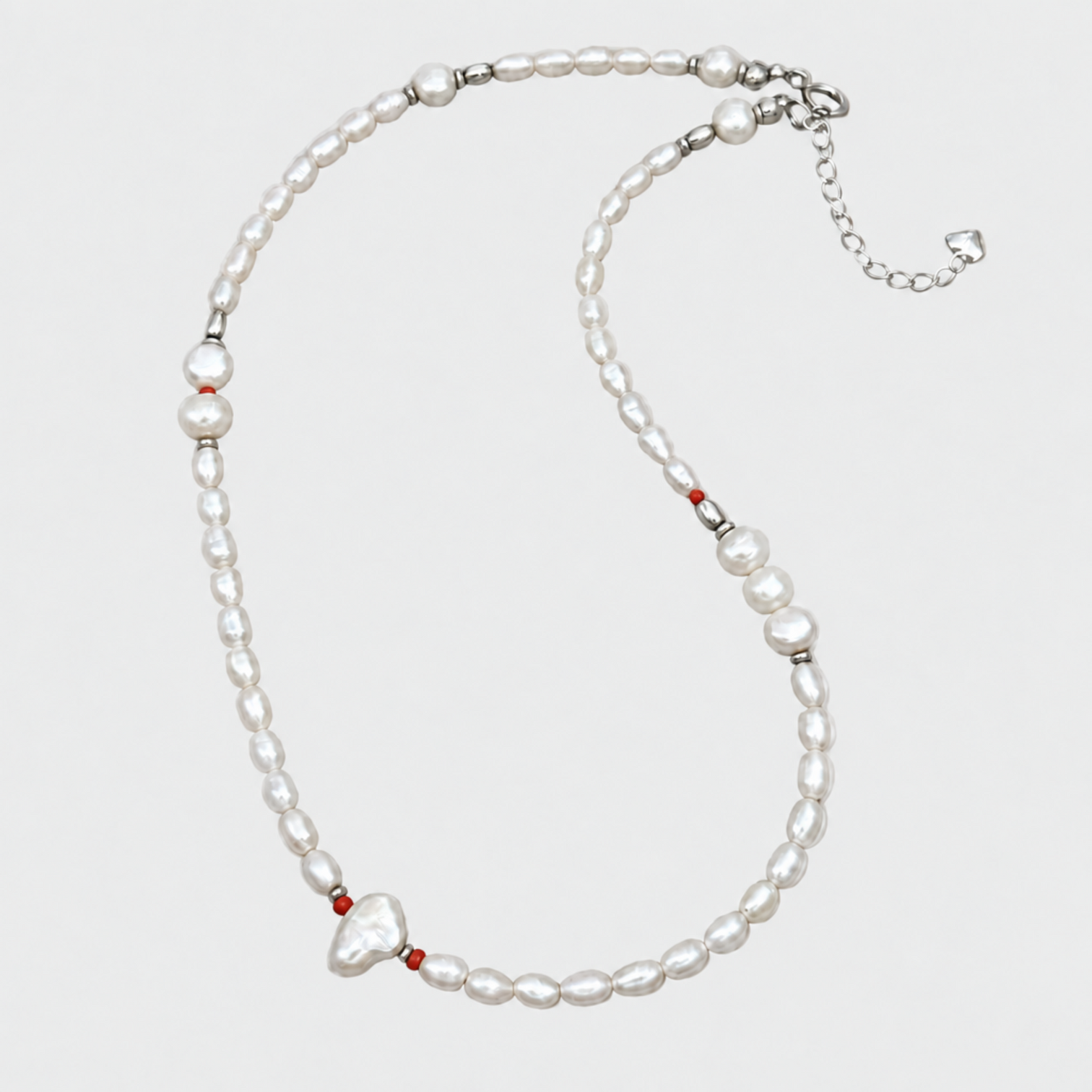 NORA white pearl necklace with red coral beads, a baroque pearl, silver clasp and extension chain on a very light grey background.