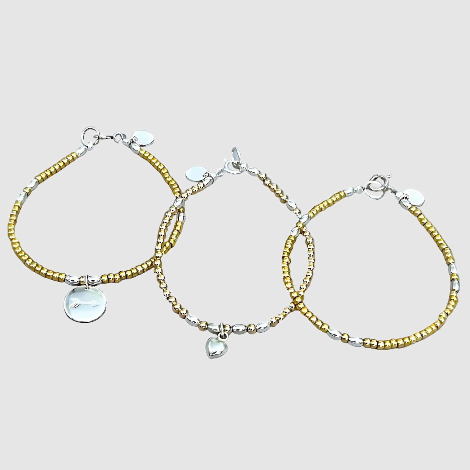 The LeBijouBijou Streak of Gold Trio Bracelets are made with yellow, pink and sterling silver. The bracelet trio is displayed on a light grey background. Styling image; this listing is for one bracelet.