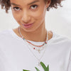 Closer view of model wearing the ALAIA Necklace made with freshwater white pearls, the GINGER Neckace made with Sunstones and Sapphires, Sterling Silver Chain Necklaces with a Smiley Charm and a Hamsa-Peace charm.