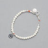 The ALAIA Bracelet is made with cultured freshwater white pearls, a sterling silver smiley charm and elements and a touch of coral. 