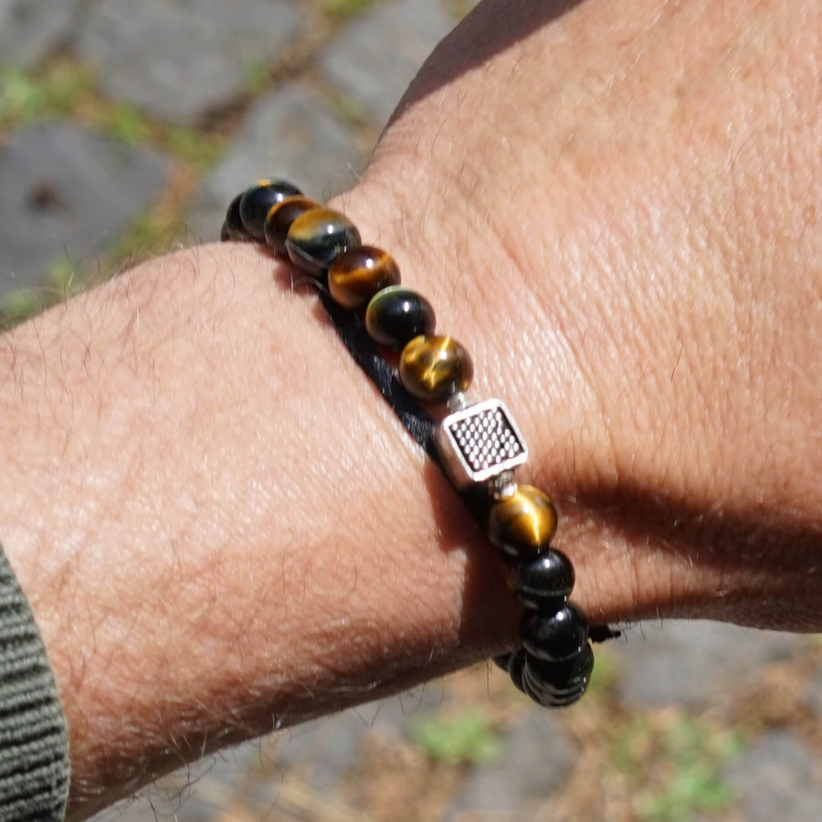 Detailed Close-up of the Chey Bracelet on a male model's wrist.  Blue Tiger Eyes Beads and the Sterling Silver Element are shown. 