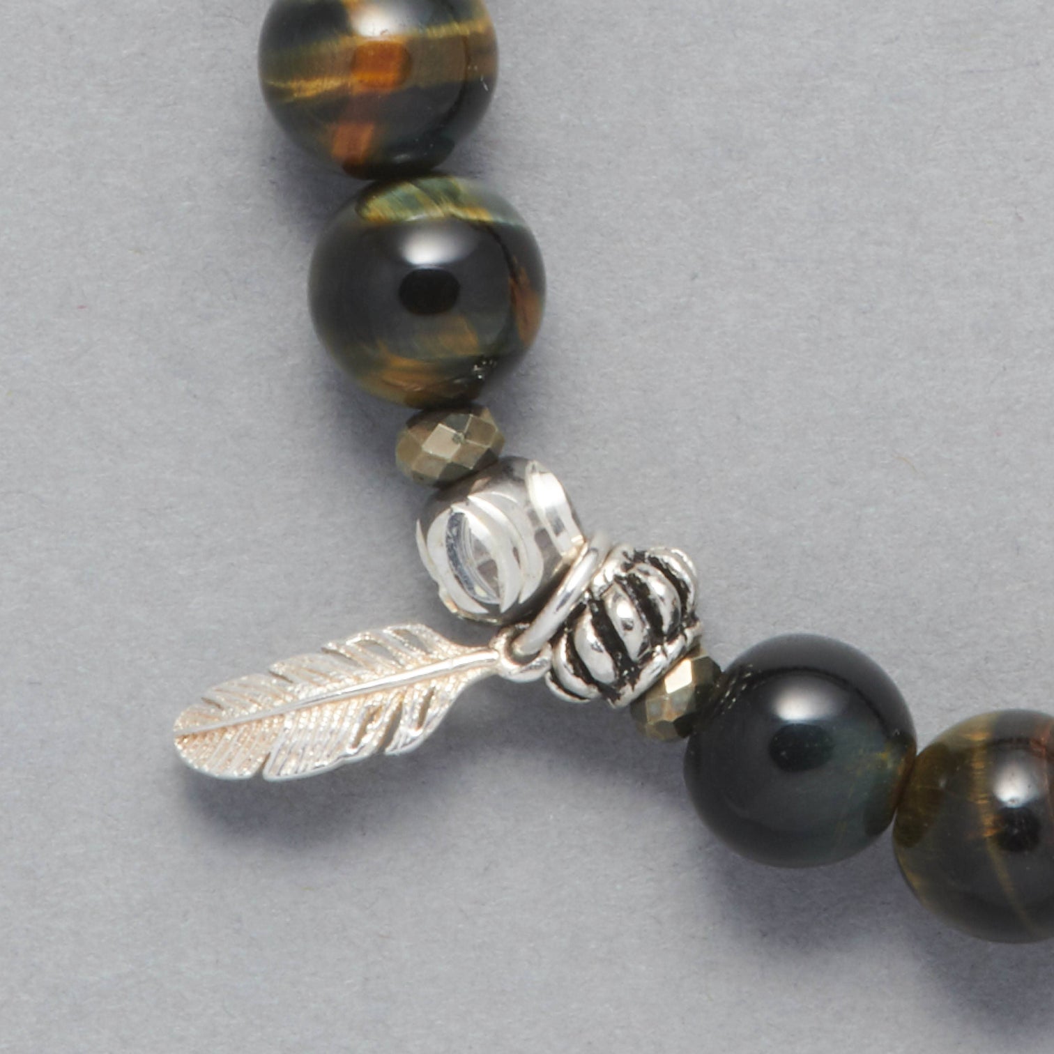 Detail of the Cheyenne bracelet made with Blue Tiger Eye, Sterling Silver Elements and a Sterling Silver feather charm. 