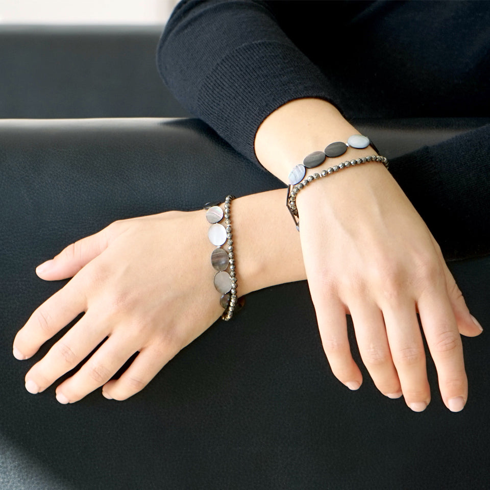 Close-up of a female model.  She is wearing the ELEA Double Wrap Bracelet made with Mother of Pearl and Pyrite. 
