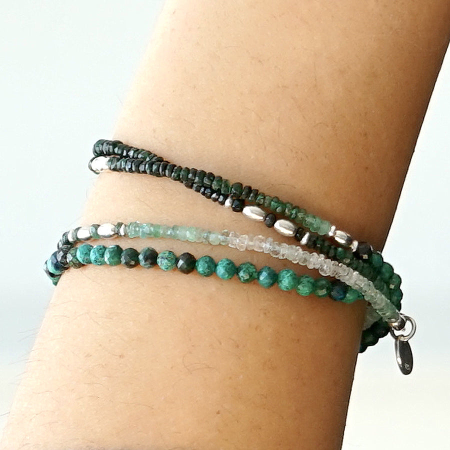 Close-up of a female model's arm. She is wearing the LE BIJOUBIJOU ESMERALDA Double Wrap Bracelet made with faceted Emeralds and faceted Chrysocolla.