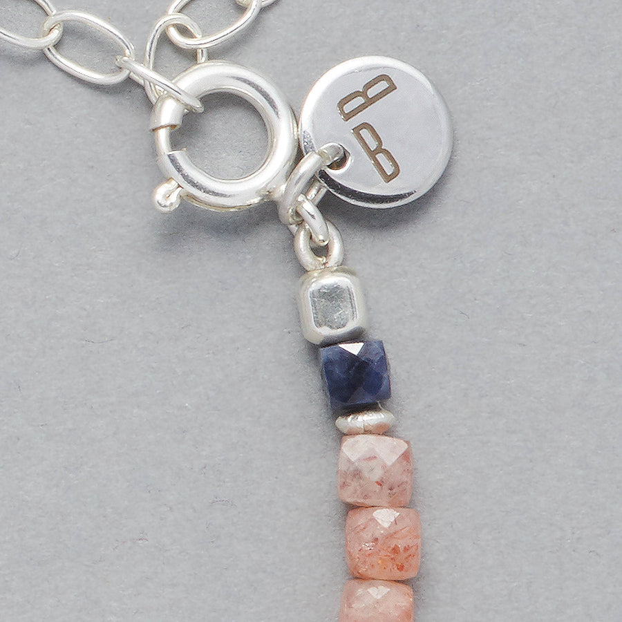 Close-Up of the Ginger Anklet made with square faceted Sunstones, faceted square Sapphires and the Le BijouBijou Sterling Silver charm.