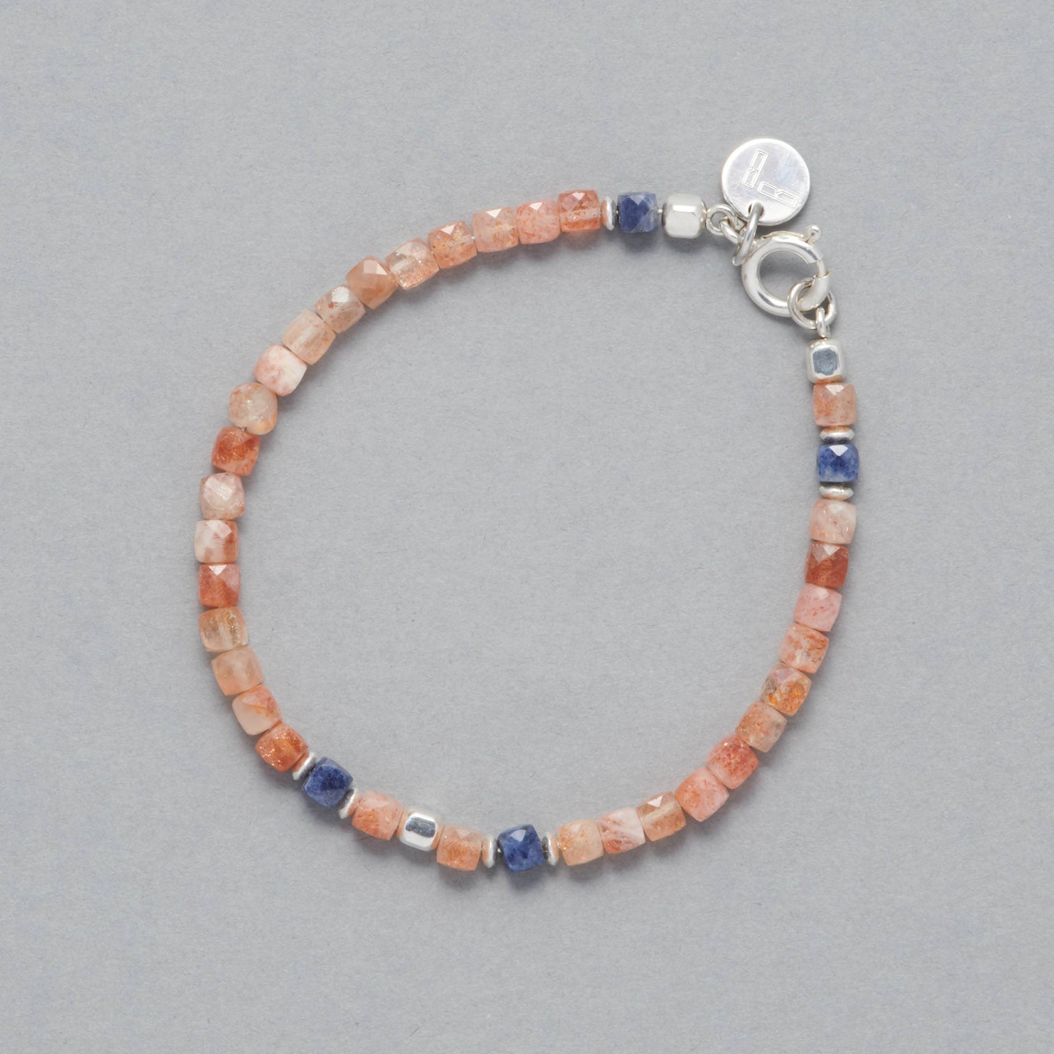 Product shot of the Ginger Bracelet made with faceted square Sunstones, faceted square Sapphires and Sterling Silver elements. 