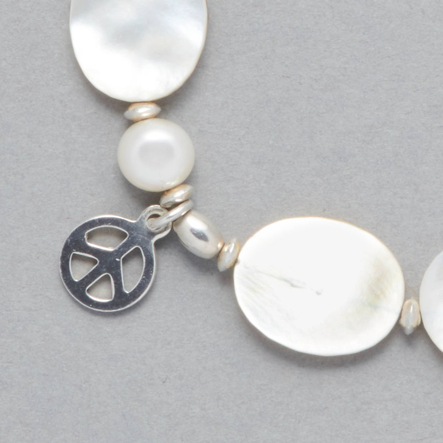 Detail shot of the MARILLA Bracelet made with Freshwater White Pearls, Mother of Pearl, Sterling Sliver elements and a Peace Symbol Charm. 