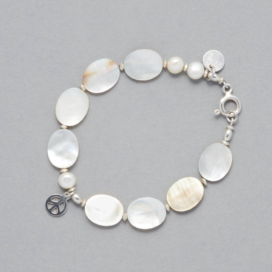 Product shot of the MARILLA Bracelet made with Freshwater White Pearls, Mother of Pearl, Sterling Sliver elements and a Peace Symbol Charm. 