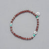Product shot of the Sia Bracelet made with faceted Garnet, Turquoise and Sterling Silver elements.